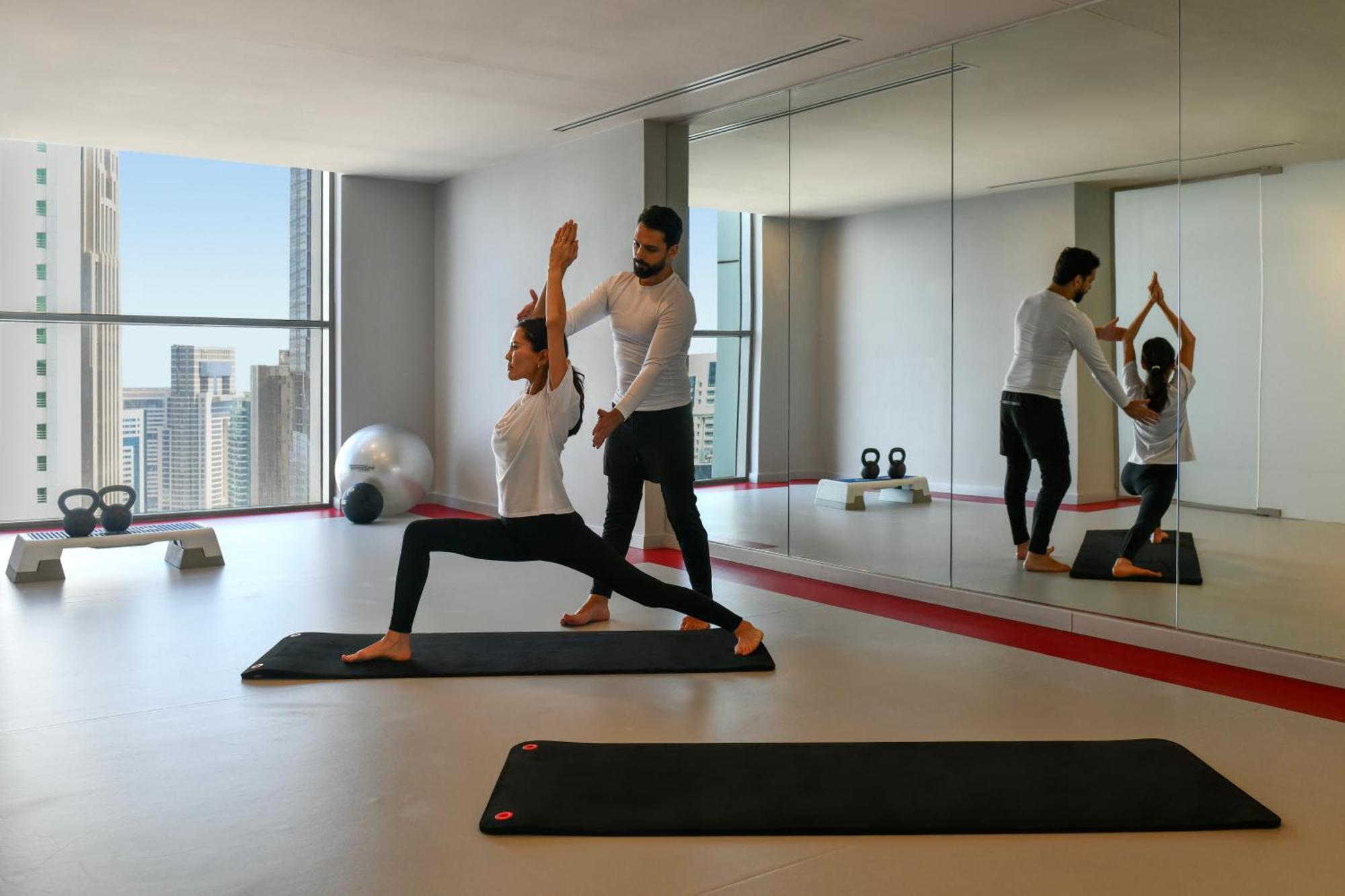 Dusit Doha Hotel Exteriér fotografie A personal trainer assisting a woman with a yoga workout